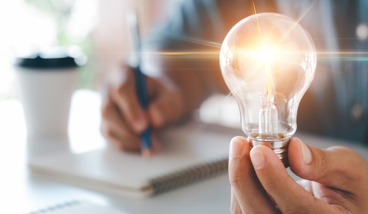 a man holding a glowing lightbulb while having an idea